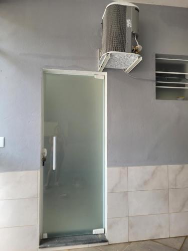 a shower in a bathroom with a fan on the wall at Aconchego Sagrada face 2 in Aparecida