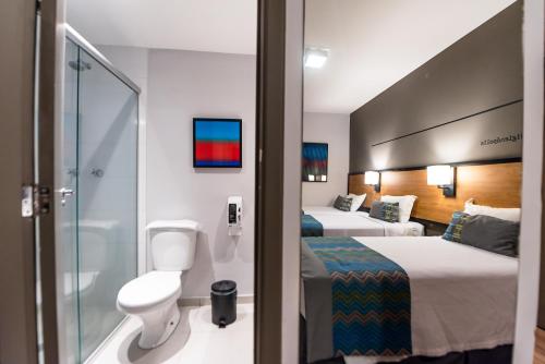 a hotel room with two beds and a shower at Monreale Lifestyle Higienópolis São Paulo in Sao Paulo