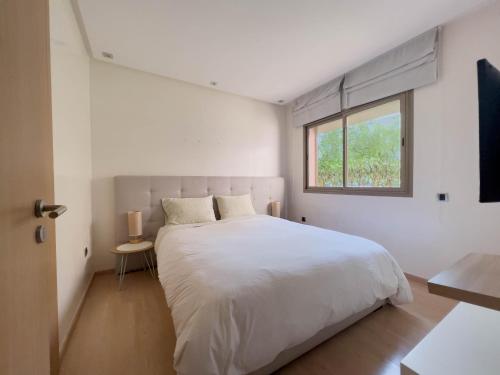 ein Schlafzimmer mit einem großen weißen Bett und einem Fenster in der Unterkunft Les Jardins Du Paradis 3 chambres avec golf et parking gratuit in Marrakesch