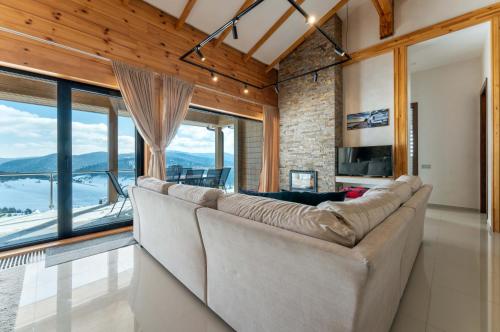 a living room with a large couch and large windows at Vila Cigota Zlatibor in Zlatibor