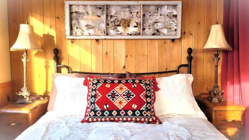 - une chambre avec un lit doté d'un oreiller rouge et de deux lampes dans l'établissement La vieille ferme, Écogîte, à Saint-Fulgence