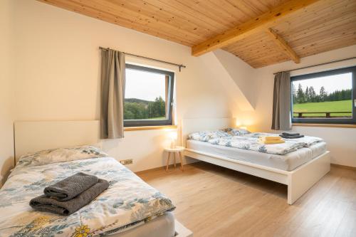 two beds in a room with two windows at Apartmány Na šumavské louce in Stachy