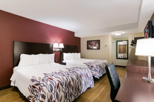 a hotel room with two beds and a desk at Red Roof Inn Hershey in Hershey