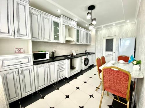 une cuisine avec des placards blancs et une table avec des chaises dans l'établissement Апартаменты 2 комнатная в новом ЖК, à Aqtöbe