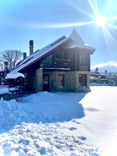 a log cabin in the snow with the sun behind it at Sofiya in Mykulychyn