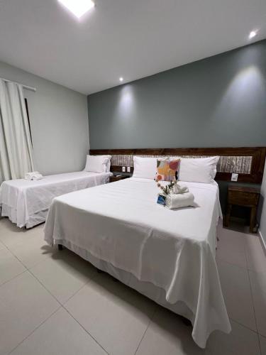 a bedroom with two beds with white sheets at Terra Bella Pousada in Morro de São Paulo