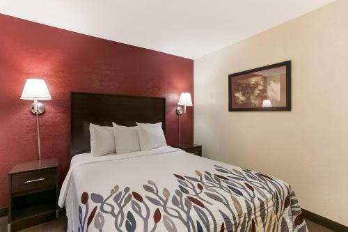 a hotel room with a bed and a red wall at Red Roof Inn Hershey in Hershey