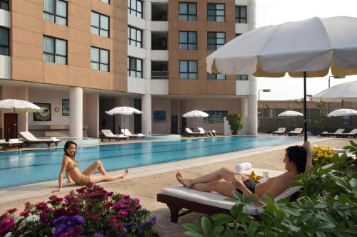 Dos mujeres están sentadas en una piscina en un hotel en Somerset Grand Hanoi, en Hanói