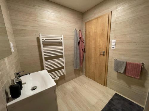 baño con lavabo blanco y puerta de madera en Apartmán HM, en Horní Maršov