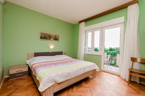 a green bedroom with a bed and a window at Apartment Ivanka in Banjol