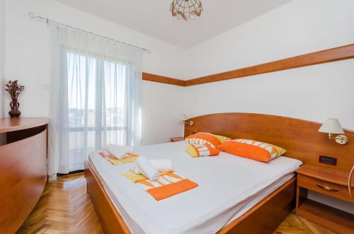 a bedroom with a large bed with orange and white pillows at Apartments Zorka in Kampor