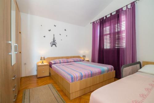 a bedroom with two beds and purple curtains at Apartments Tolj in Igrane