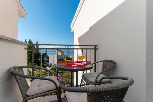 a balcony with two chairs and a table with a glass of wine at Apartments and Rooms Nikola in Omiš