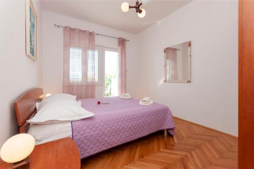 a bedroom with a purple bed and a window at Apartments and Rooms Nikola in Omiš