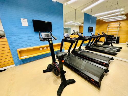 a gym with several treadmills and a blue wall at Mediterrâneo 507 - Todo Equipado, Ar Condicionado, Churrasqueira na Varanda, Internet Fibra 600MB, Estacionamento Grátis in Cabo Frio