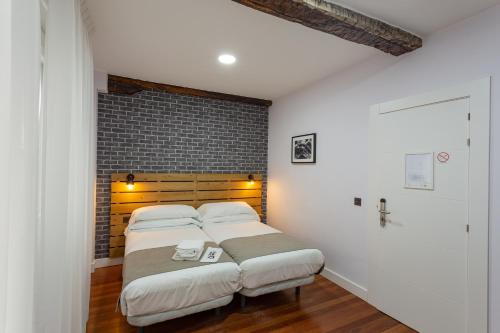 a bedroom with two beds and a brick wall at Casual Mardones in Bilbao