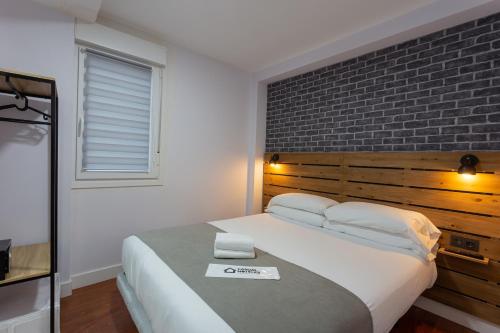 a bedroom with a large bed with a brick wall at Casual Mardones in Bilbao