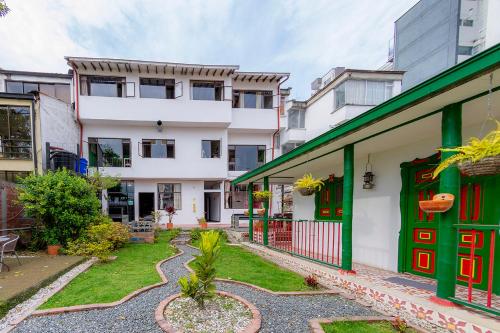 un groupe de bâtiments avec des portes vertes et une cour dans l'établissement Ayenda Mountain Hostels Manizales, à Manizales