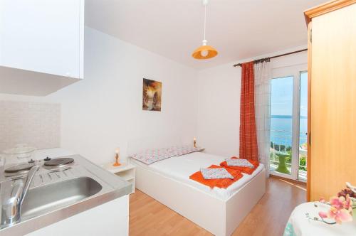 - une petite cuisine blanche avec un lit et un évier dans l'établissement Apartments Zorica, à Tučepi