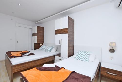 two beds in a room with white walls at Apartments Ivanovic in Budva