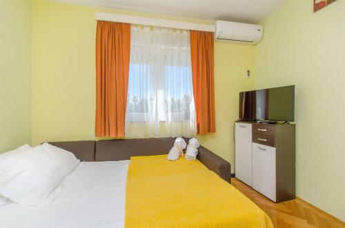 a hotel room with a bed with a television and a window at Apartment Studenka in Makarska