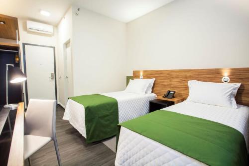 a room with two beds with green and white sheets at Travel Inn Hotels Wise Indaiatuba in Indaiatuba