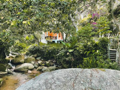 a stream in a garden with a house in the background at Casa del Arroyo 2-Bedroom Cottage Fireplace and BBQ in Jarabacoa