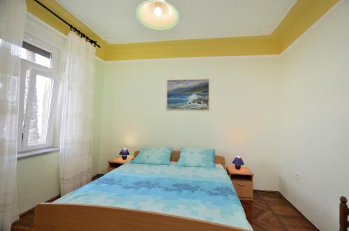Schlafzimmer mit einem Bett mit blauer Bettwäsche und einem Fenster in der Unterkunft Apartments Romina in Rijeka