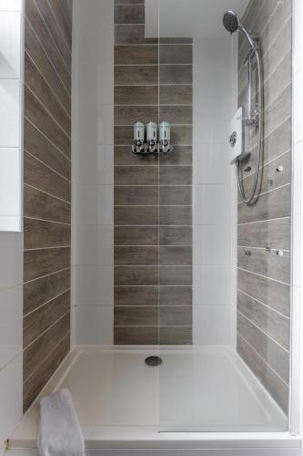 a bathroom with a bath tub with a shower at Snuggle Cove Apartments By Bella Vita Stays in Liverpool