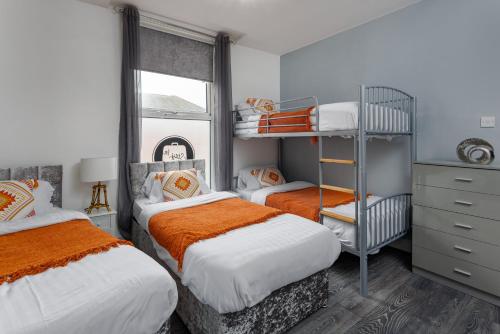 1 dormitorio con 2 camas con sábanas de color naranja y blanco en Snuggle Cove Apartments By Snazzy Short stay en Liverpool