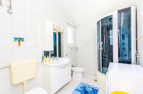 a white bathroom with a toilet and a sink at Apartments Kazimir in Nečujam