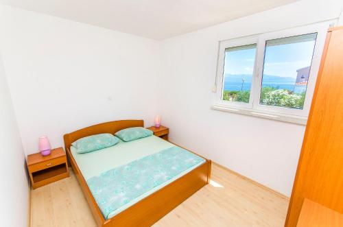 a small bedroom with a bed and a window at Apartments Kazimir in Nečujam