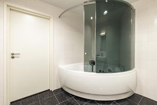 uma banheira branca numa casa de banho com uma porta de vidro em AirHome - Raekoja Plats em Talin