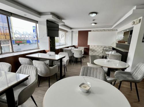a restaurant with white tables and chairs and a window at Hotel Imperial in Ambato