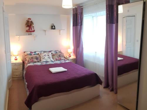 um quarto com uma cama com lençóis roxos e um espelho em TravelStop #Ealing em Londres