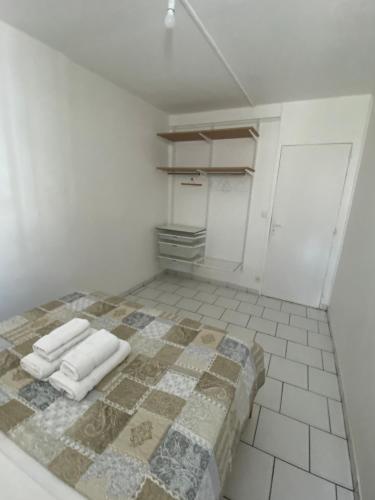 Habitación con suelo de baldosa, cama y toallas. en Appartement moderne, 2 chambres, proche aéroport • CHU • port en Les Abymes
