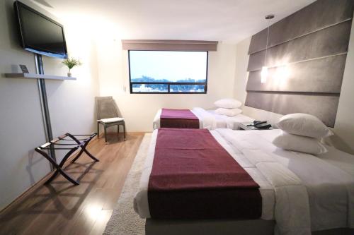 a hotel room with two beds and a flat screen tv at Hotel Posada Tulancingo in Tulancingo