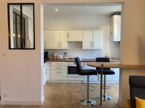 a kitchen with white cabinets and a table and chairs at 27 boulevard Féart in Dinard