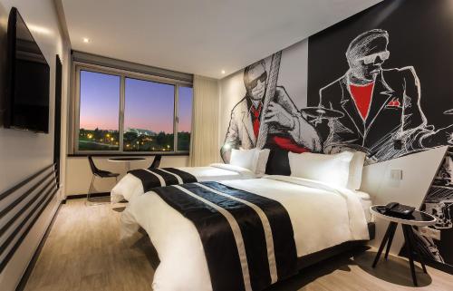 two beds in a hotel room with a painting on the wall at HF Fenix Music in Lisbon