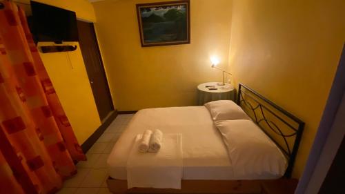 Dormitorio pequeño con cama y TV en Hostel Pura Vida en Liberia, en Liberia