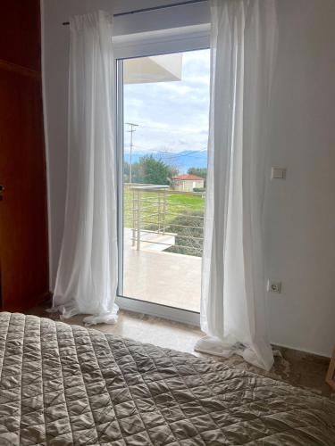 a bedroom with a bed and a large glass window at Villa Delfini in Chrani
