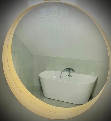 a bathroom with a white tub in a round mirror at Chata Jarabáček in Loučná nad Desnou