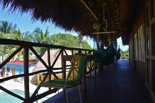 a porch with chairs and a hammock on a beach at Cabañas Frida in Chelem