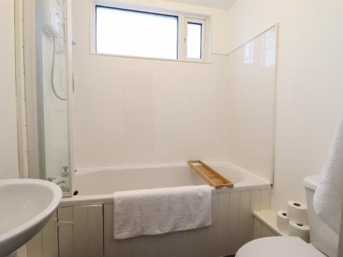a white bathroom with a tub and a sink at 1 Llwyn Hir in Blaenau-Ffestiniog