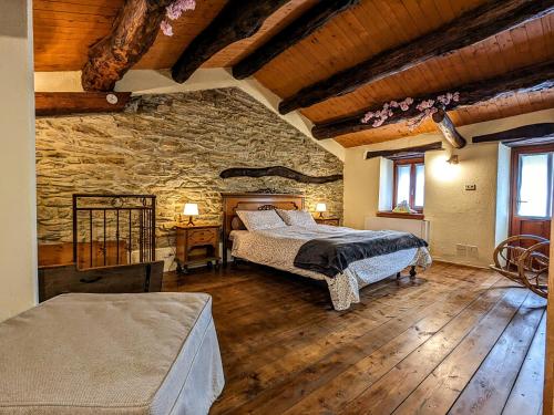 a bedroom with two beds and a stone wall at Casa Nenella in Paesana