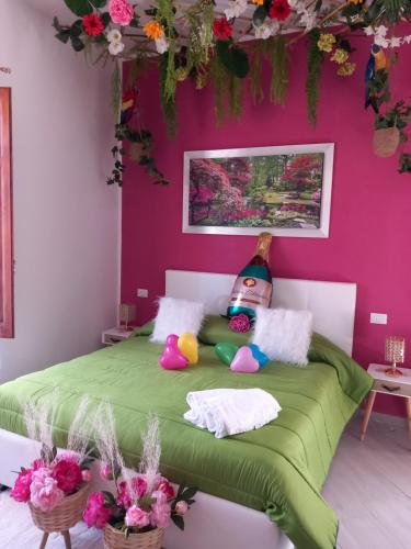 una camera con un letto verde e una parete rosa di Mary Gery's Rooms a Castellammare del Golfo