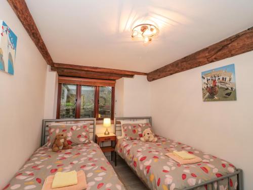 2 camas en una habitación con 2 ositos de peluche en The Old Granary, en Beaminster