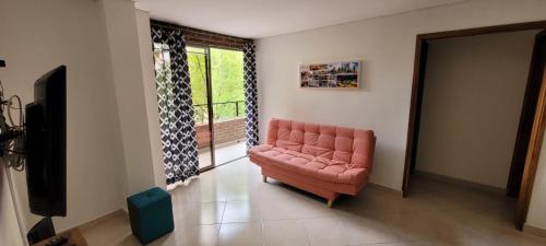 sala de estar con sofá rosa y ventana en MEDELLÍN SURAMERICANA APARTAMENTO 3, en Medellín