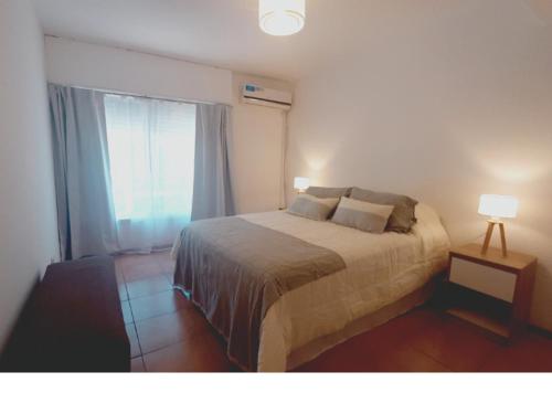 1 dormitorio con 1 cama con 2 lámparas y una ventana en La Jarilla en Mendoza