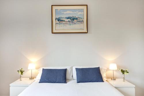 - un lit blanc avec des oreillers bleus et une photo sur le mur dans l'établissement Casa Valeta, à Barcelone